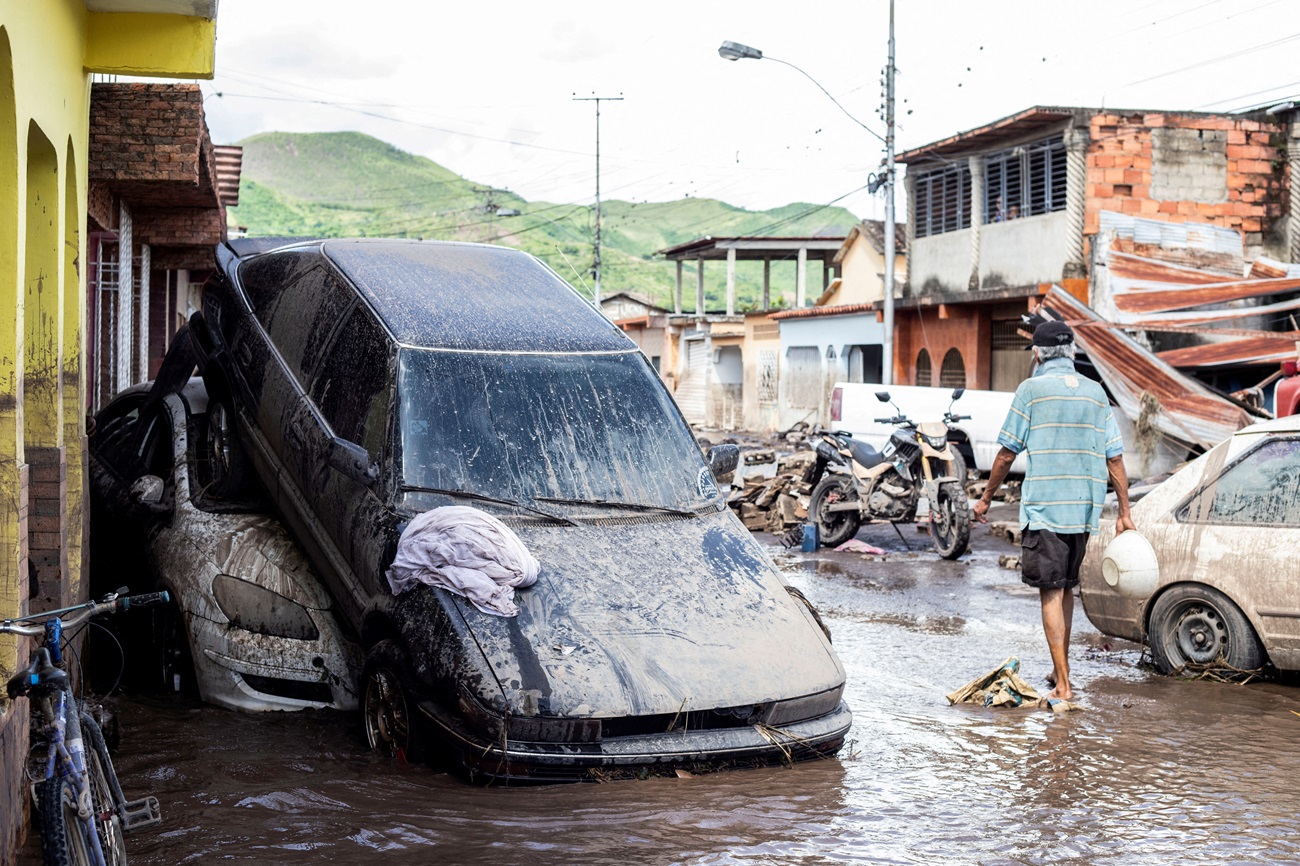 A man walks near damaged vehicles in Cumanacoa, Venezuela after floods caused by Hurricane Beryl...