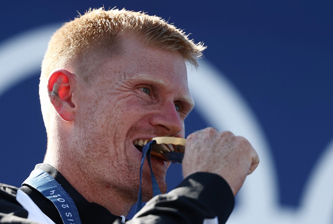 New Zealand's Finn Butcher bites his medal as he celebrates winning gold. Photo: Reuters