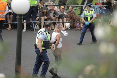 Police escort a woman from Parliament grounds this morning. Photo: RNZ