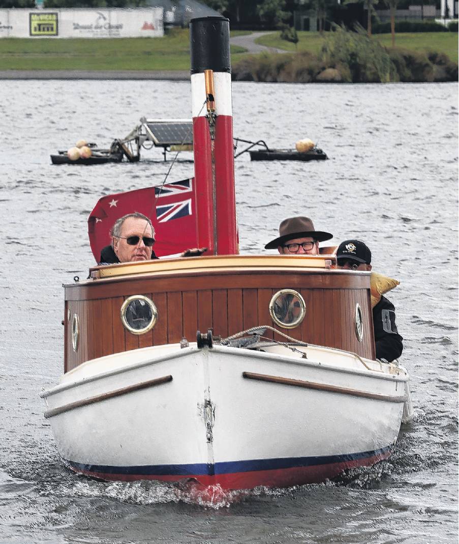 Dan Gordon (right) peeks over the wheelhouse of Allan Familton’s replica steam launch as it...