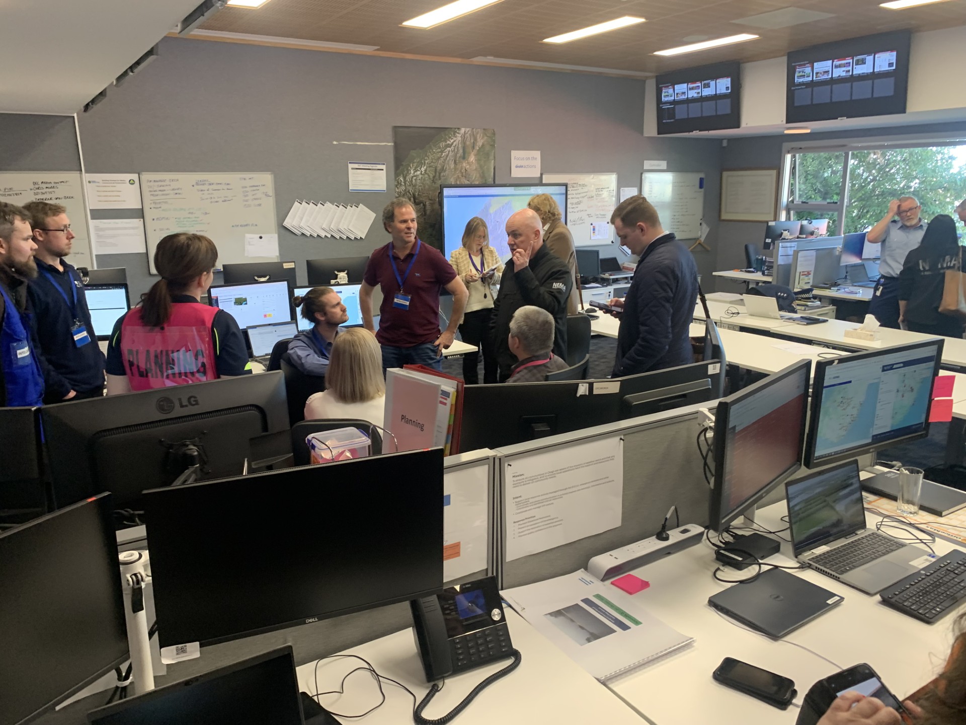 Team members from the Emergency Coordination Centre chat with Prime Minister Christopher Luxon...