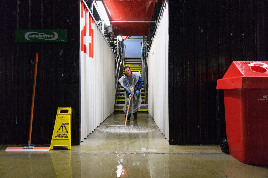 A steward works to dry the stands due to heavy rainfall prior to the Super Rugby Quarter Final...