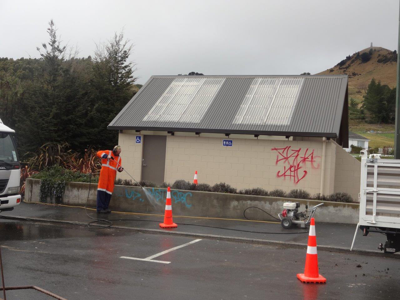 A contractor cleans off graffiti from outside the Palmerston public toilets; the interior of the...