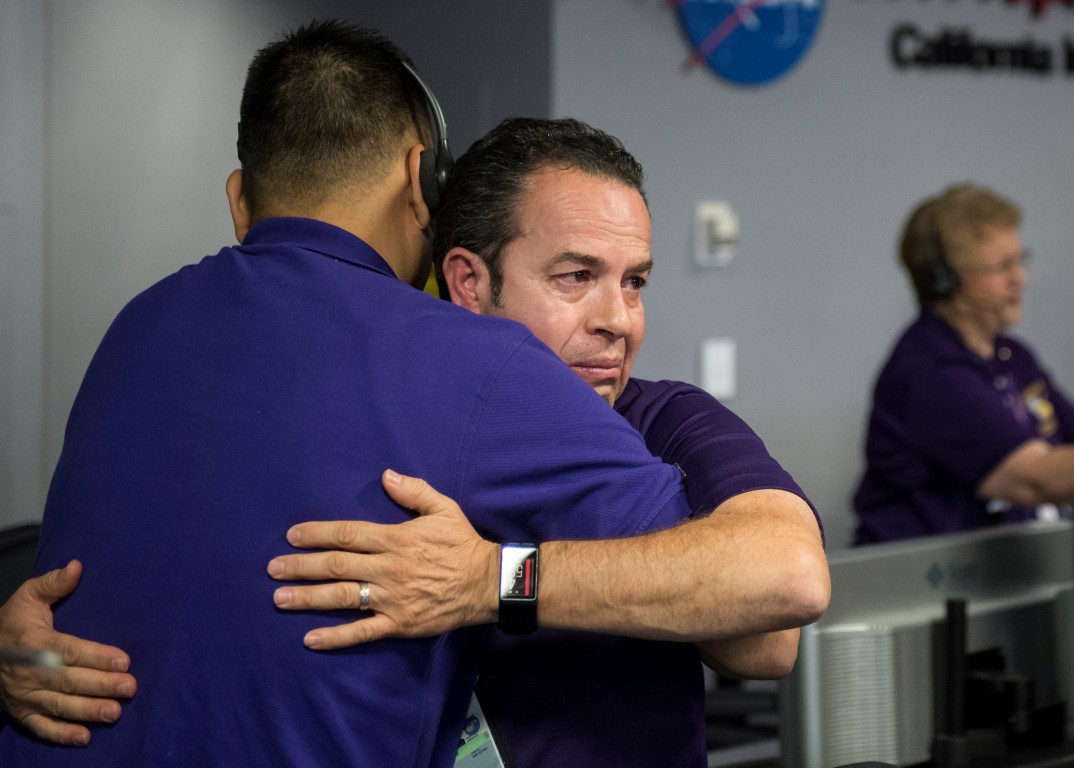 Cassini team members embrace after the spacecraft was deliberately plunged into Saturn, at NASA's...