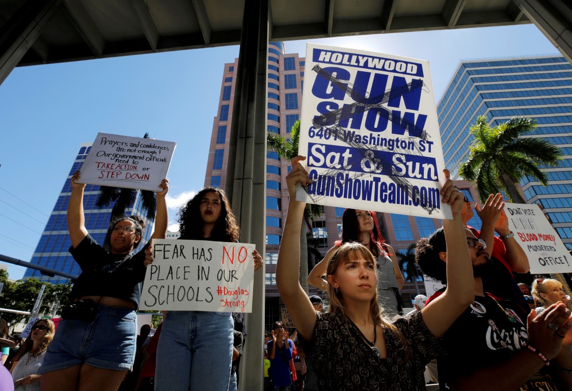 Protesters hold placards at a rally calling for more gun control in the wake of the shooting at...