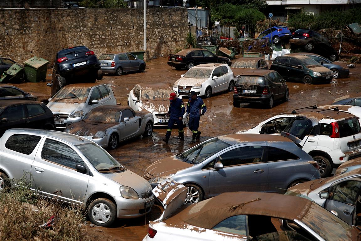 Members of a rescue team walk among damaged cars following flash floods near Athens. Photo: Reuters