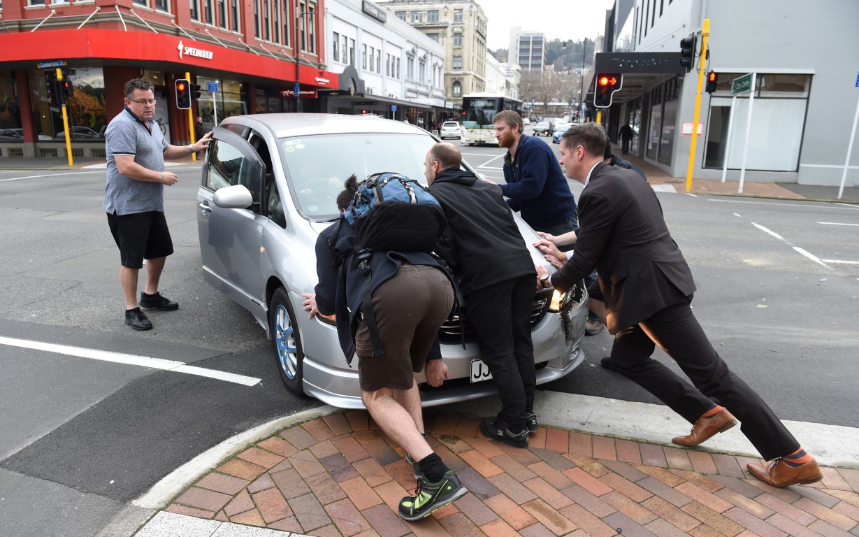 Passers-by help push a vehicle off the street following the crash. Photo: Gregor Richardson