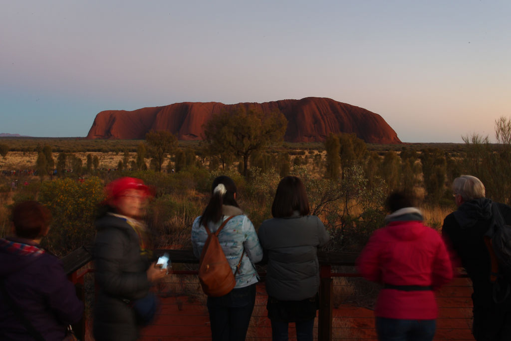 Visitors to Uluru take photos from a viewing area during sunrise. Photo: Getty