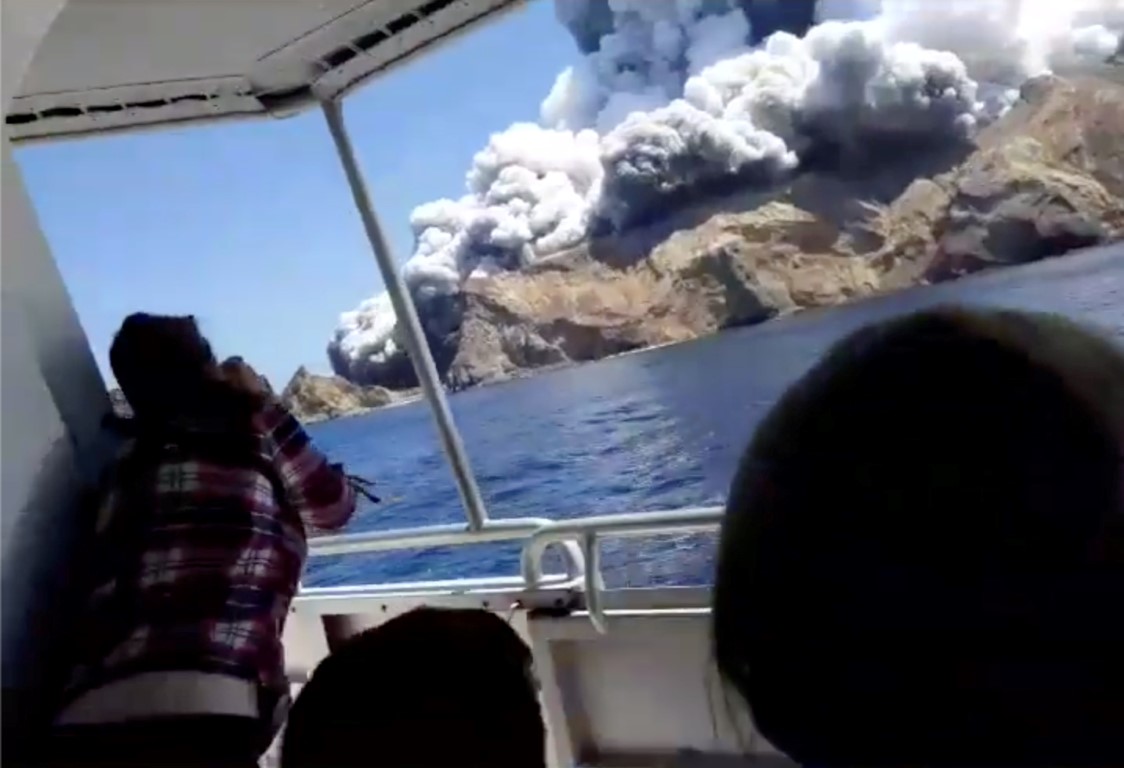 People on a boat watch as smoke billows from White Island. Photo: INSTAGRAM @ALLESSANDROKAUFFMANN...