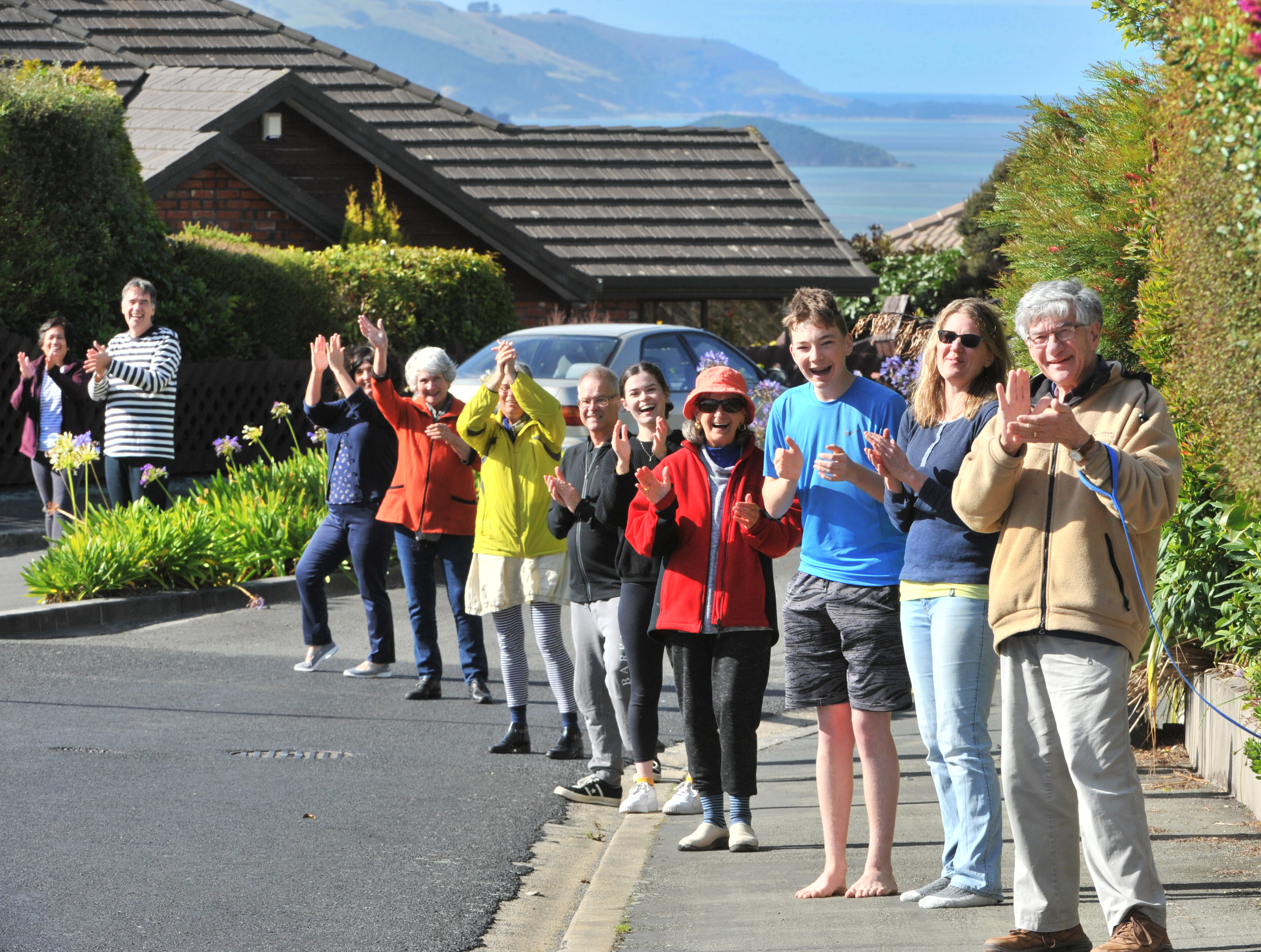 Clapping for essential workers while practising social distancing, standing 2m apart, are...