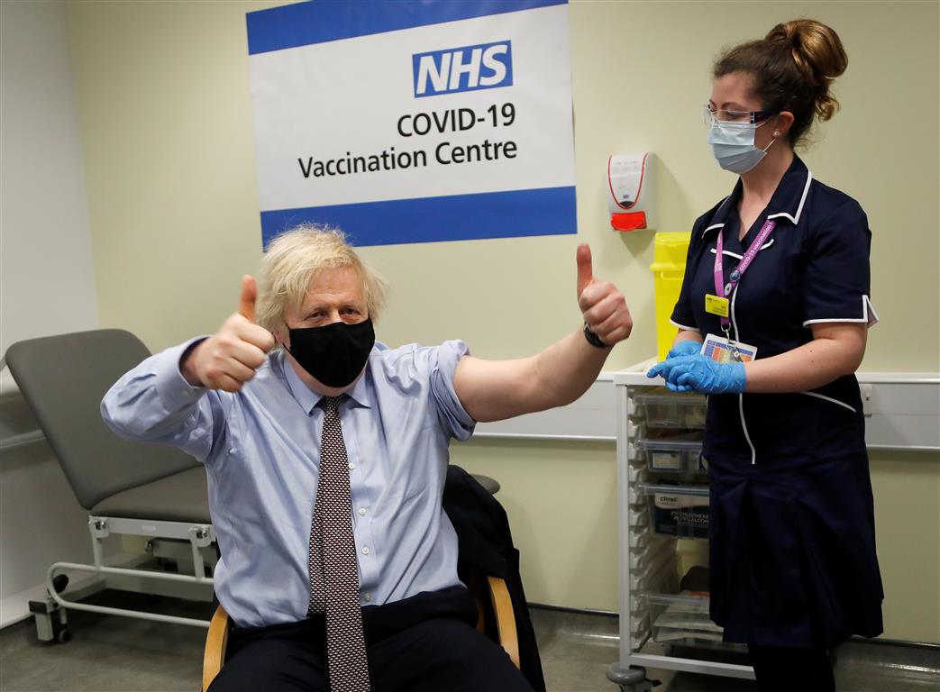 British Prime Minister Boris Johnson reacts after receiving a dose of the Oxford/AstraZeneca...