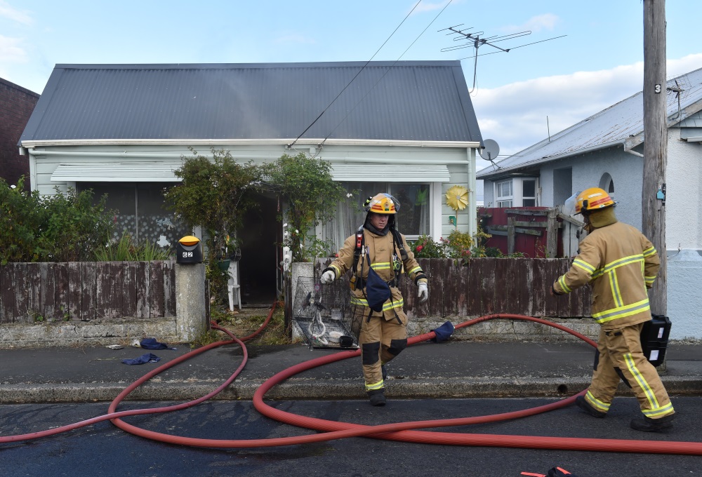 A firefighter with caged birds rescued from the home. Photo: Gregor Richardson  