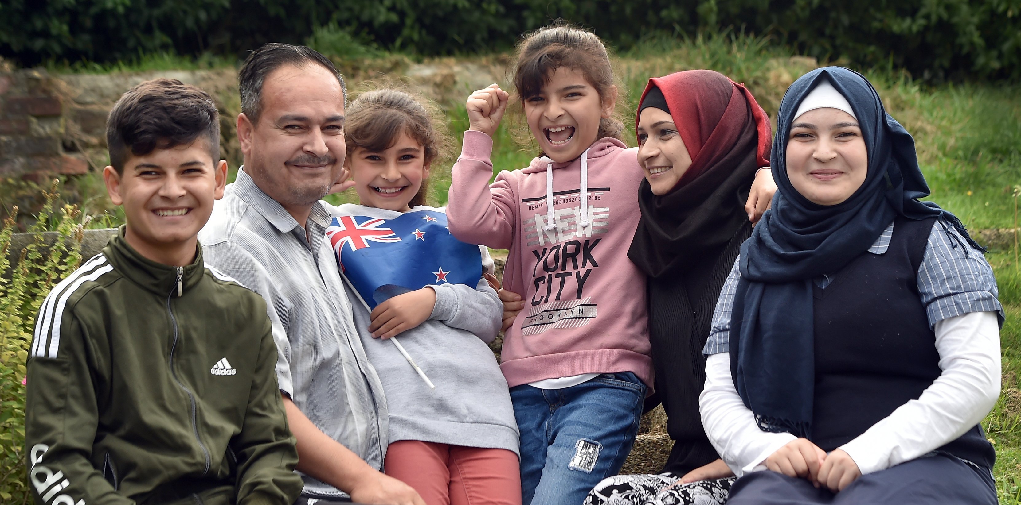 Showing off their new flag are the Haroura family, (from left) Ousama (14), Mohamad, Lina (8),...