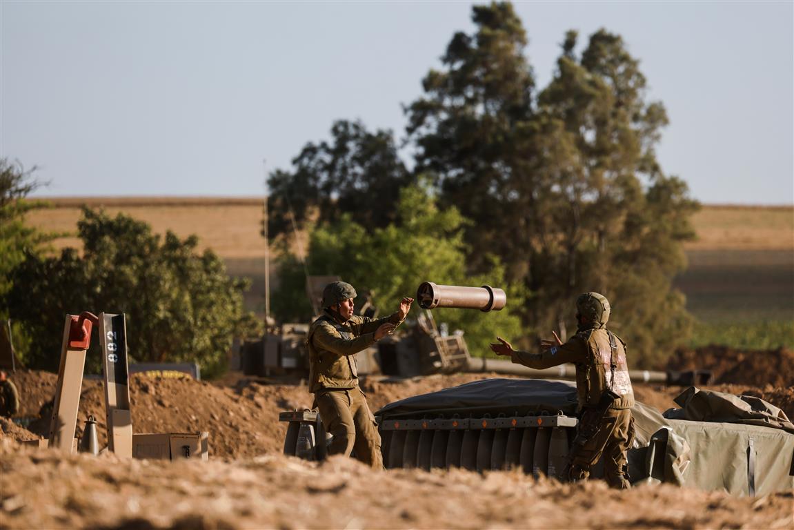 Israeli soldiers work at an artillery unit position on the Israeli side of the border between...