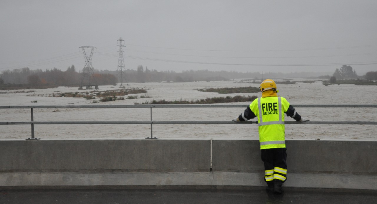 A fire volunteer keeps a keen eye on the Ashley/Rakahuri River from the Cones Road Bridge. Photo:...