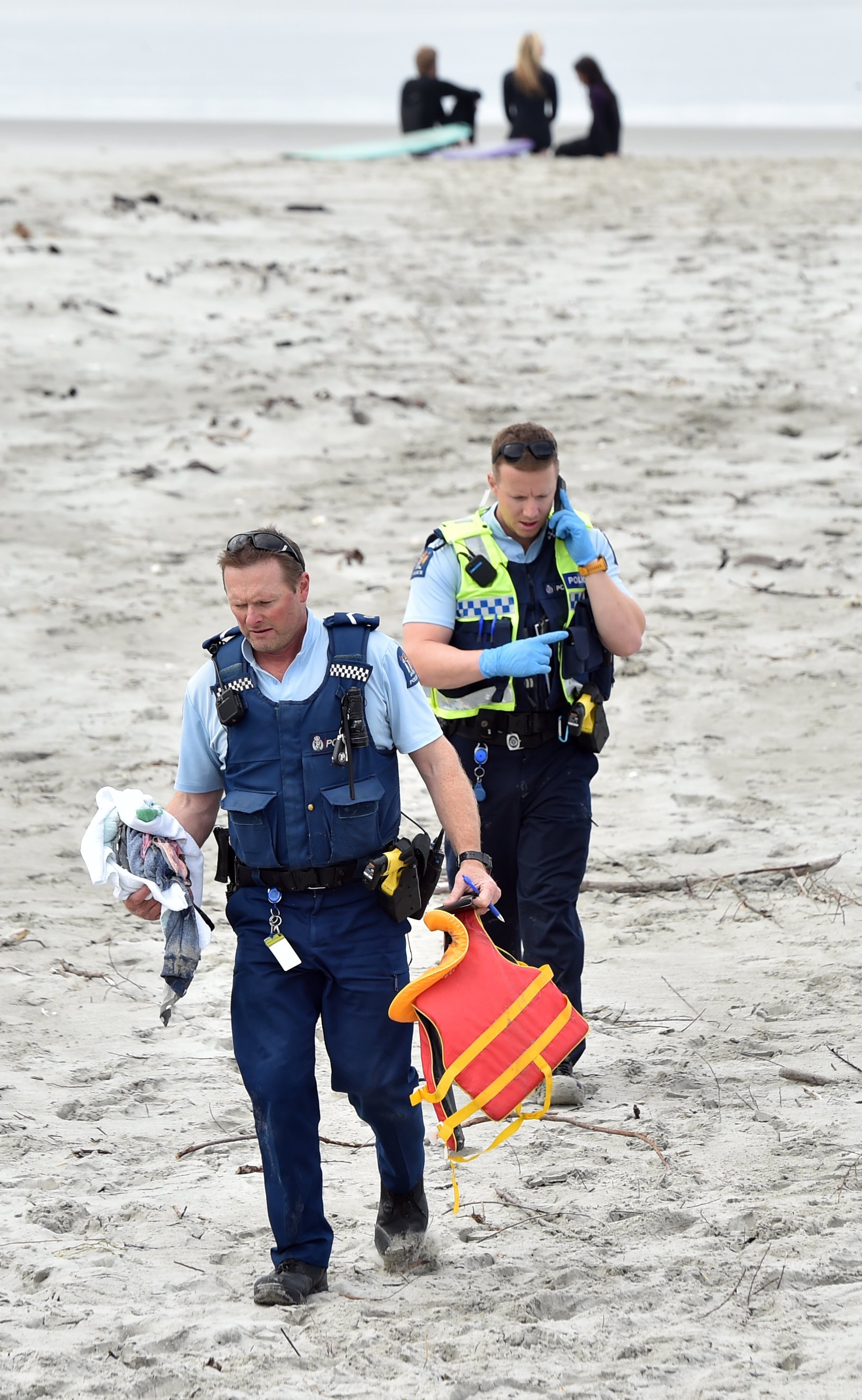 Police leave the beach with items recovered from the scene.