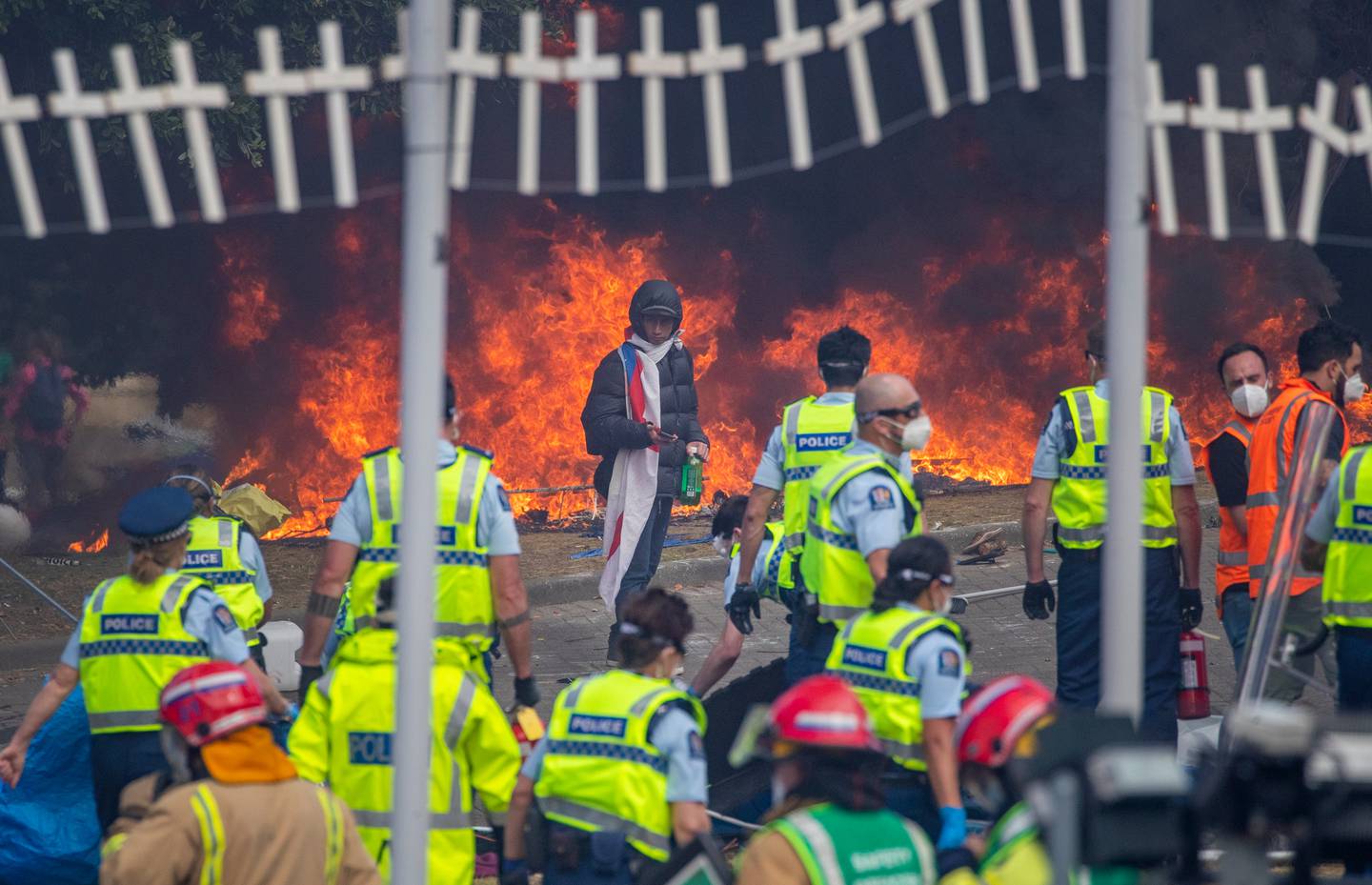 A lone protester facing police officers in front of burning tents on Wednesday afternoon. Photo:...