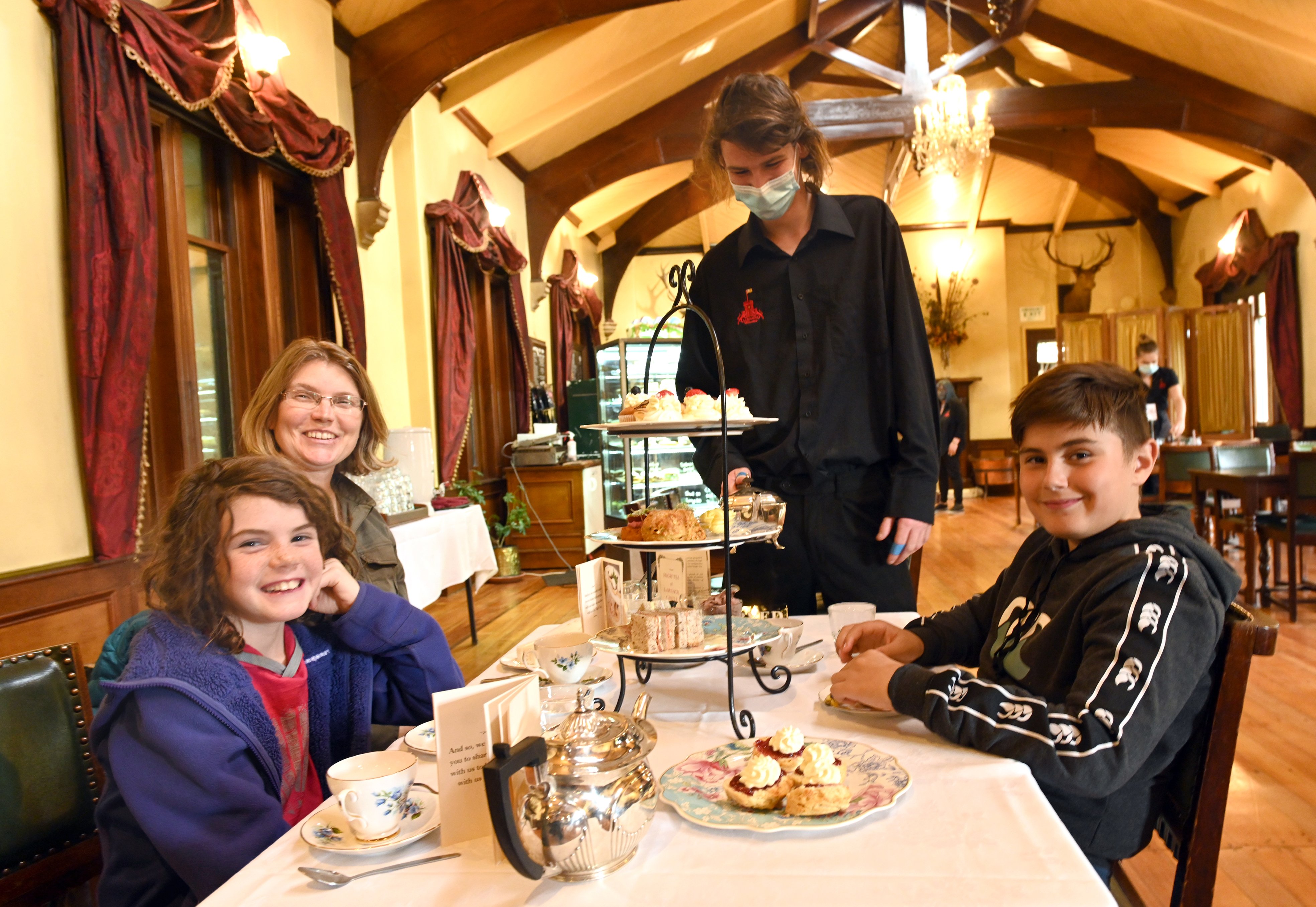 Larnach Castle front of house assistant Finn Cooper serves high tea to Stacey Walden and her...