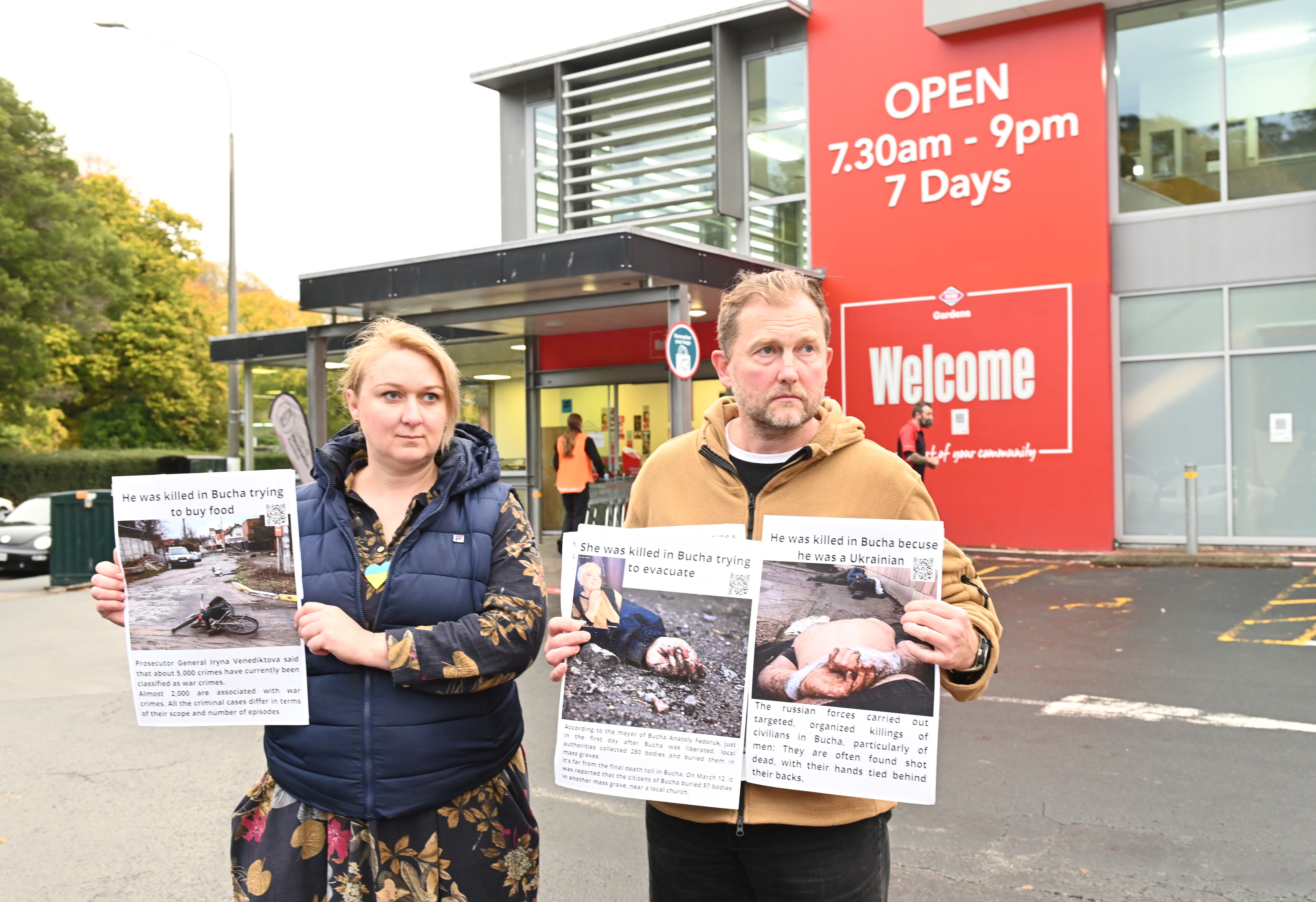 Ukrainians Olha Viazenko and her husband Oleskii Ikonnikov hold posters outside Gardens New World...