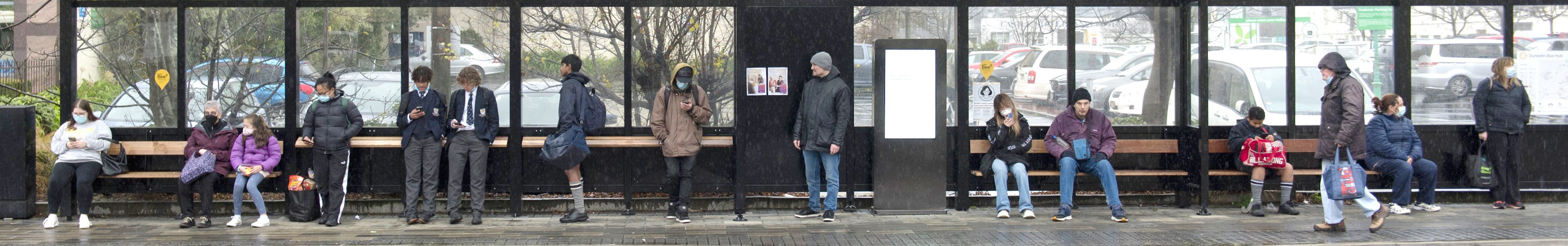 Bus patrons shelter from the rain at the bus hub in Great King St yesterday. PHOTO: GERARD O'BRIEN