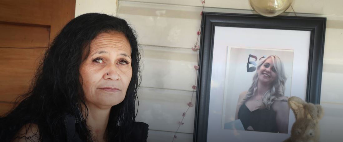 Brenda O'Shea sits next to a photo of her daughter, Jasmine Wilson, who was murdered in 2019....