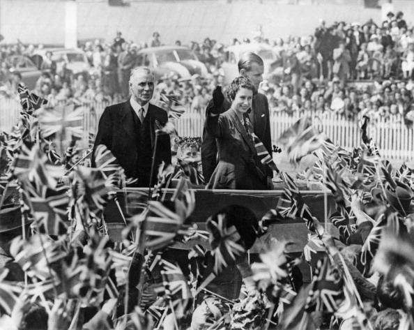 Queen Elizabeth II and Prince Philip surrounded by a mass of flag-waving children during a...