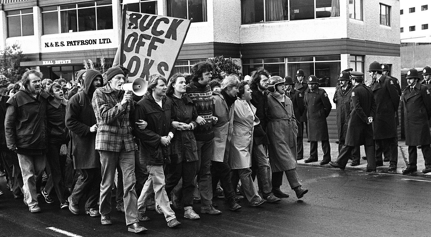 John Minto (front, with megaphone) leads an anti Springbok tour protest down Broadway in Dunedin...