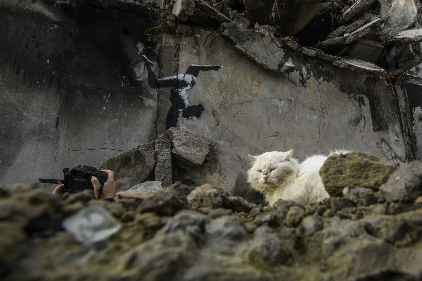 A couple of onlookers view a work from graffiti artist Banksy in the war-scarred Ukrainian town...