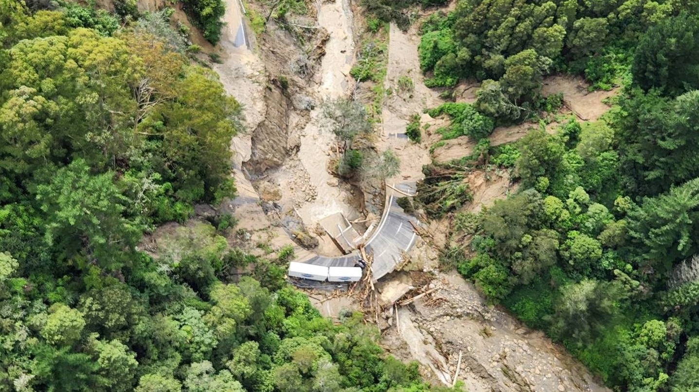 A truck-and-trailer unit surrounded by by debris on a wrecked section of State Highway 2 between...