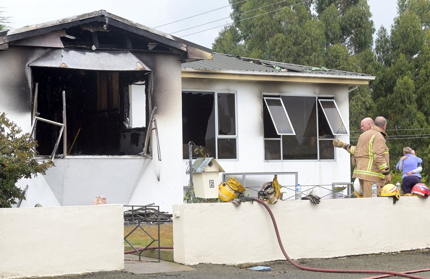 One of the occupants of a Stronsa St home is comforted by her mother as firefighters clean up the...