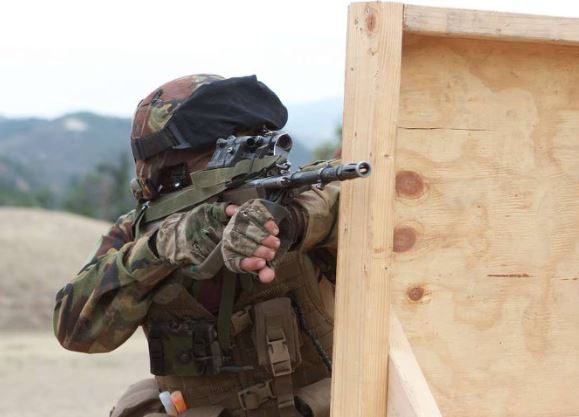 Private Dominic Abelen kneels behind a barricade while engaging targets at Range 218, Marine...