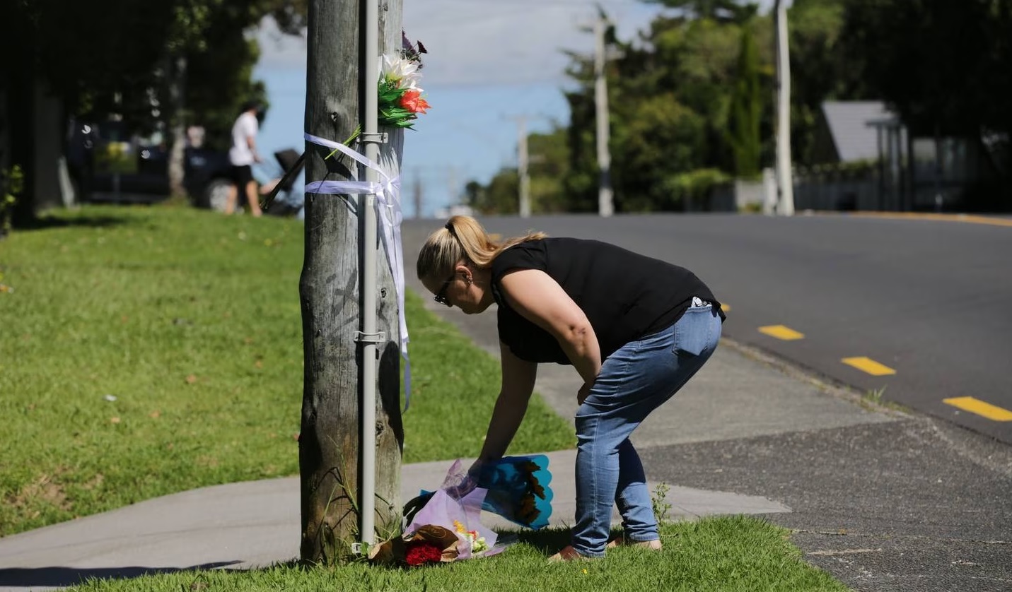 A woman lays flowers at the scene of a fatal road-rage attack in Beach Haven, on Auckland's North...