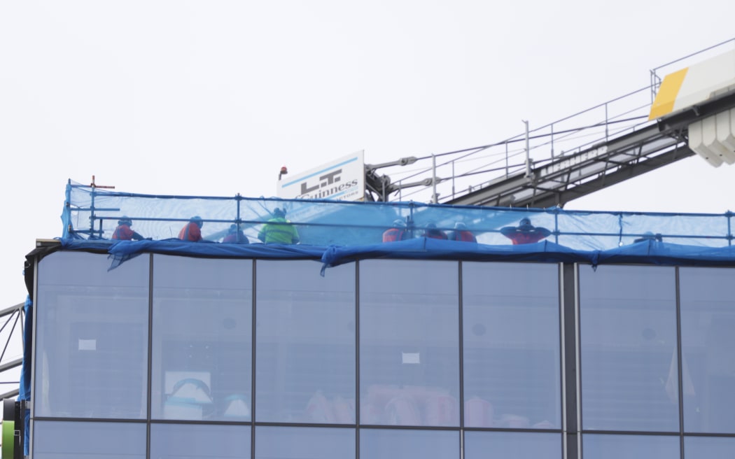 Construction workers can be seen at the top of the building at the centre of a serious shooting...