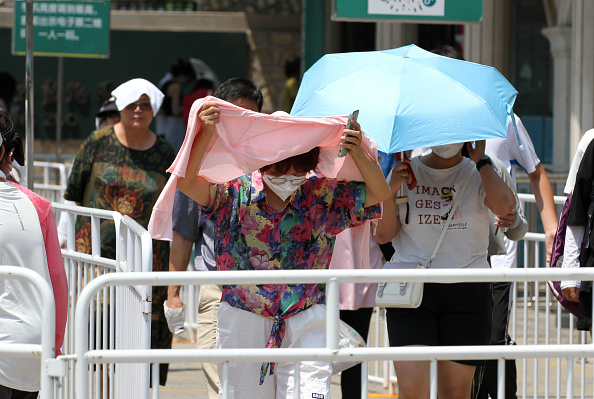 People try to screen themselves from the sun on a recent 40degC day at Beijing Zoo in China....