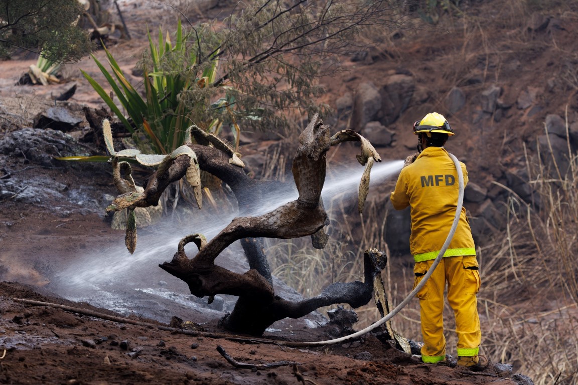 A Maui County firefighter fights flare-up fires in a canyon in Kula following the wildfires....