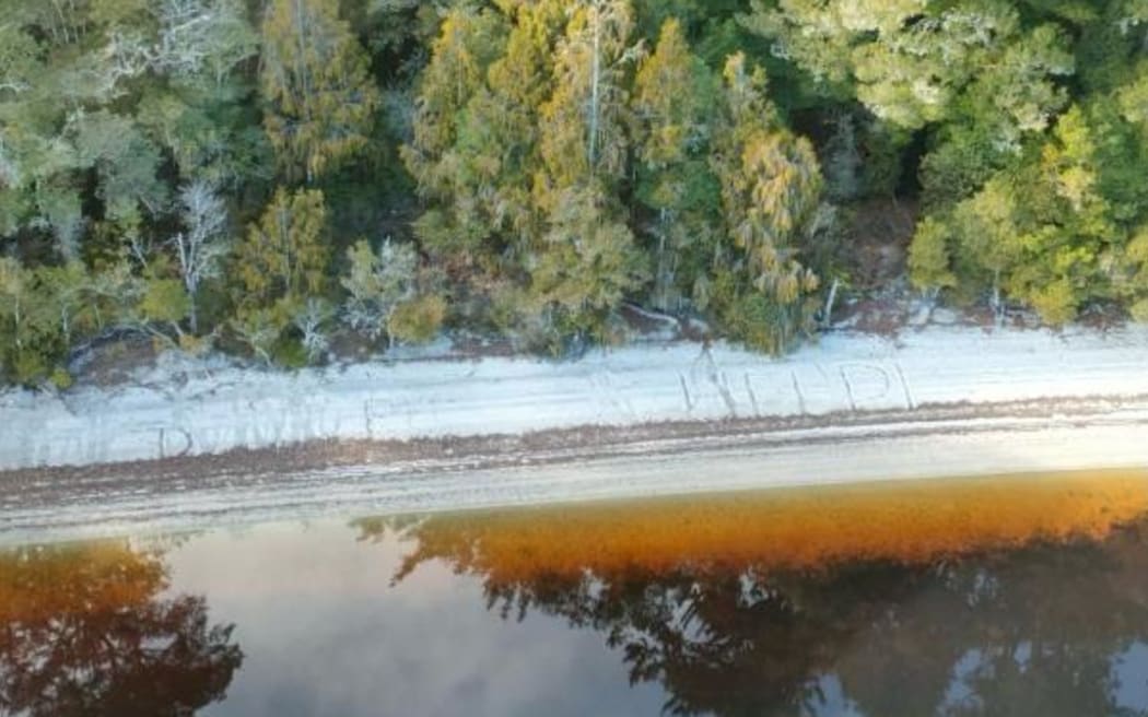 The message, right, seen in the sand at Lake Ahaura. Photo: NZ Police