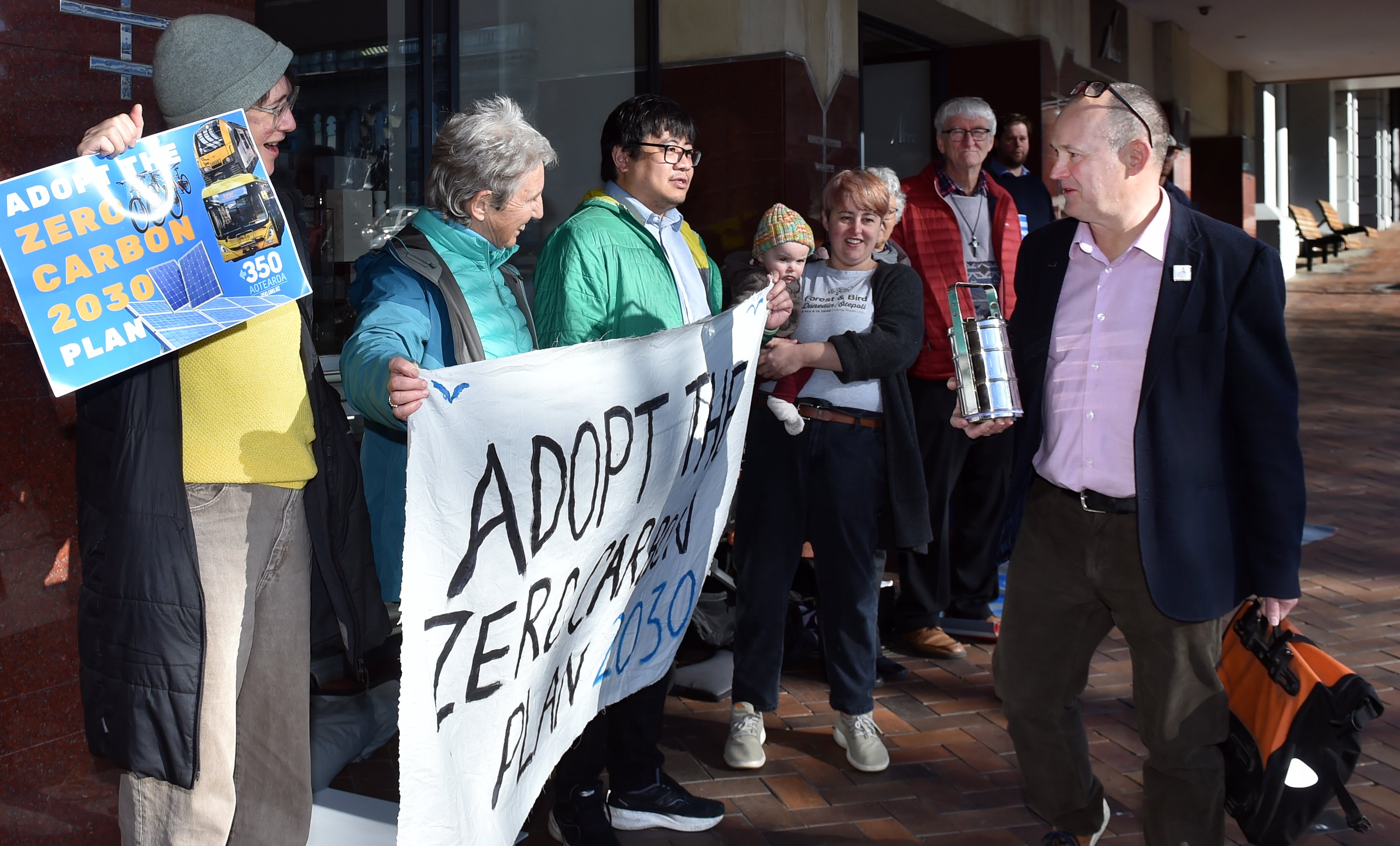 City councillor Steve Walker passes climate activists on his way into a Dunedin City Council...