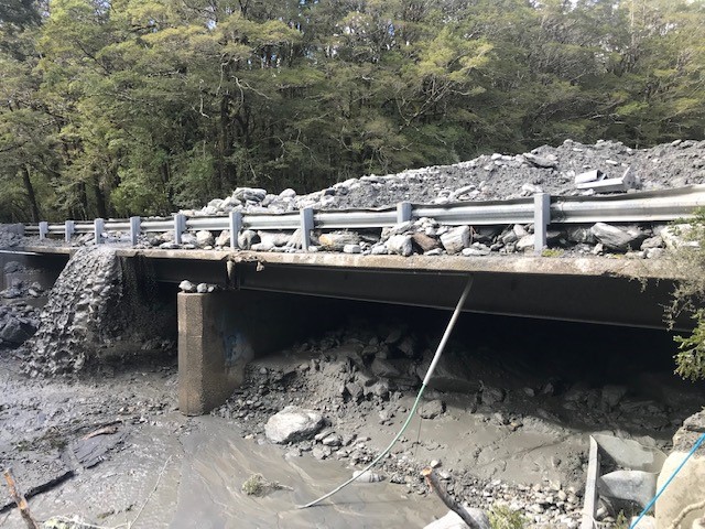 Debris covering the bridge over Muddy Creek on SH6. Photo: Waka Kotahi