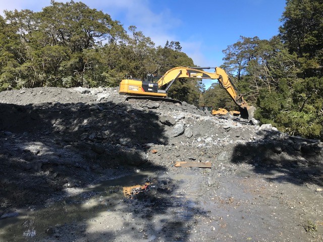 Crews work to clear the pile of debris near Muddy Creek. Photo: Waka Kotahi