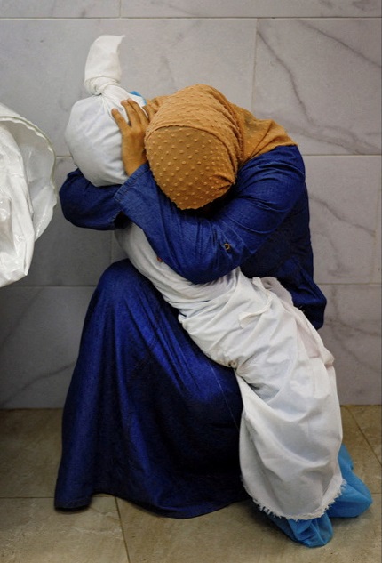 Palestinian woman Inas Abu Maamar embraces the body of her 5-year-old niece Saly, who was killed...