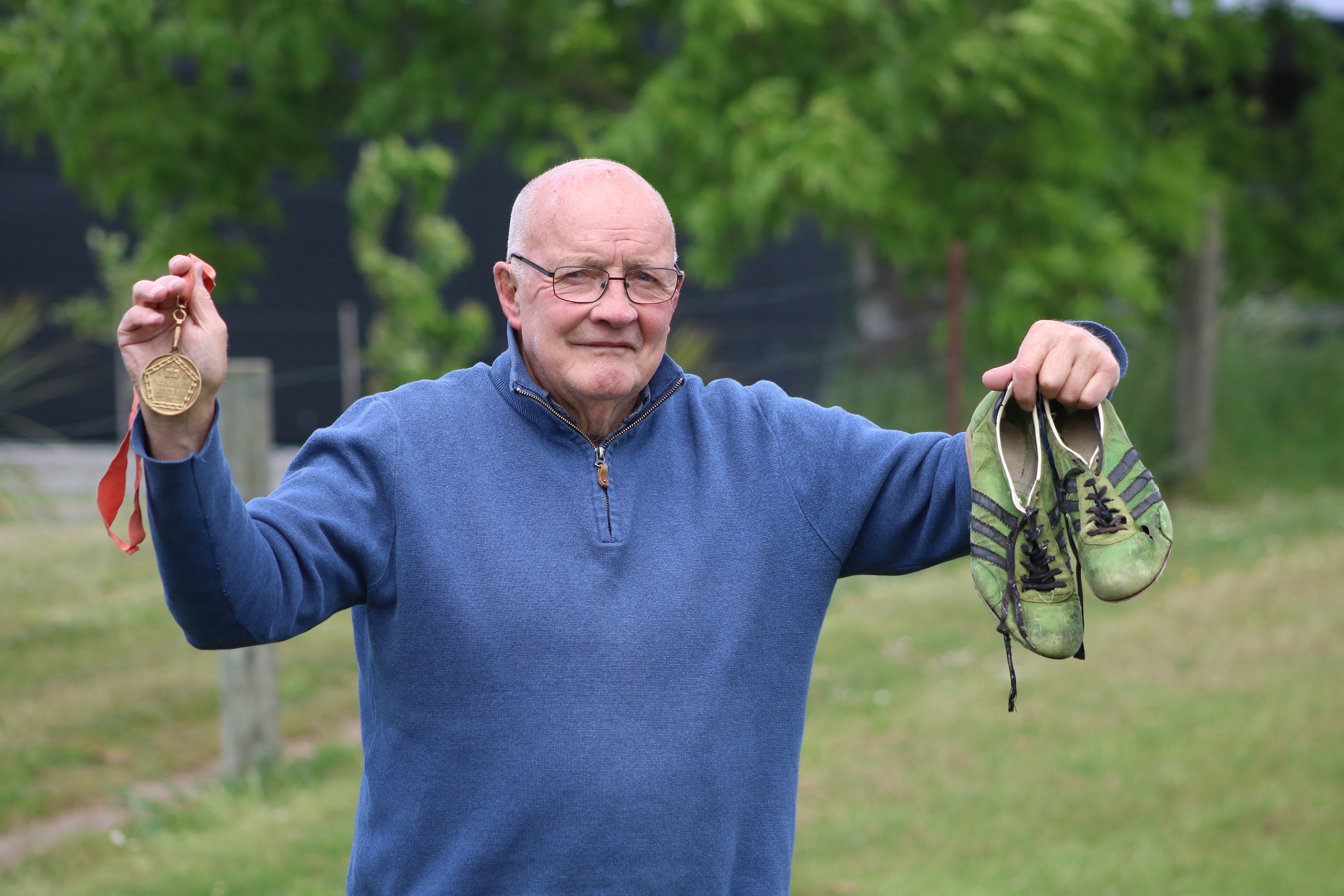 Dick Tayler, holding his gold medal and running shoes from the 1974 Commonwealth Games, is...