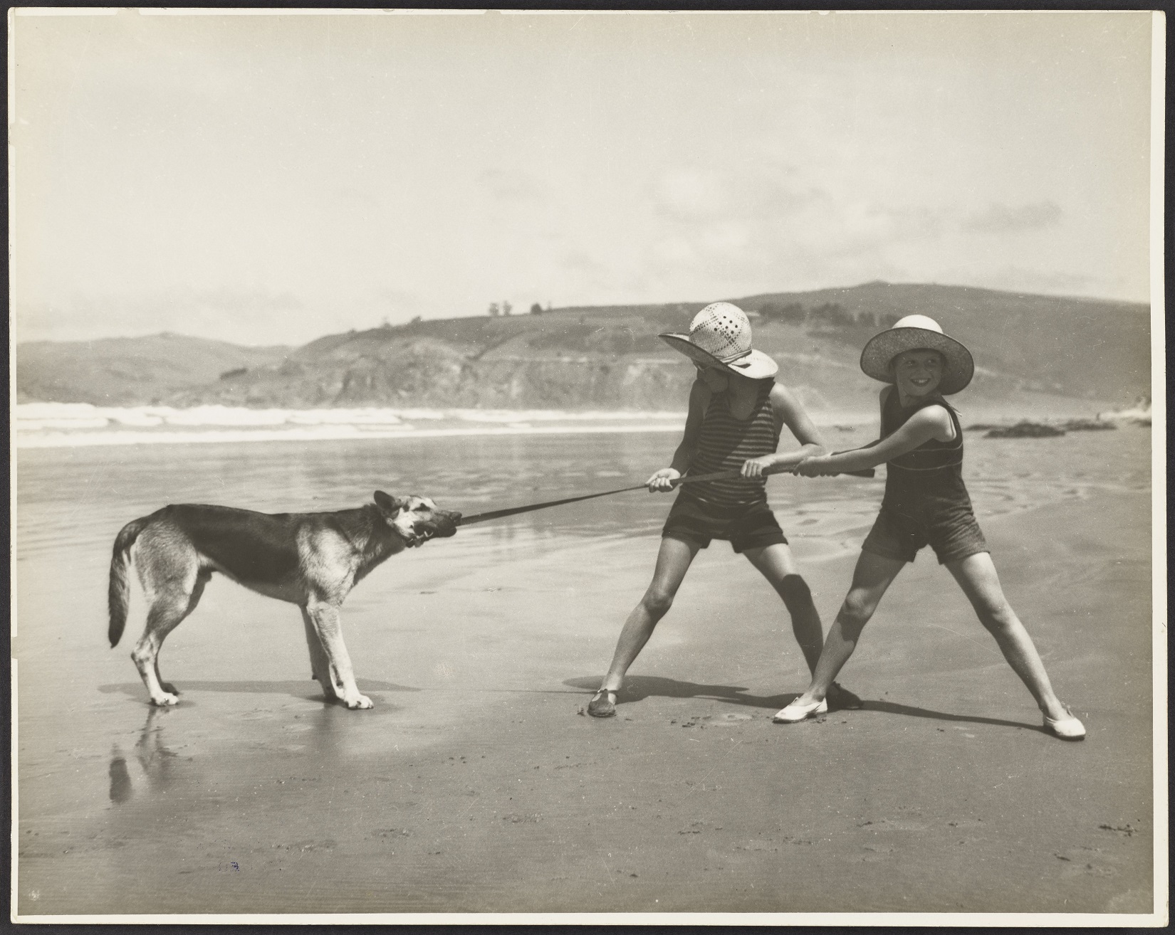 Children and a dog play tug of war at Warrington Beach, about 1930. Photo: George Chance, Hocken...