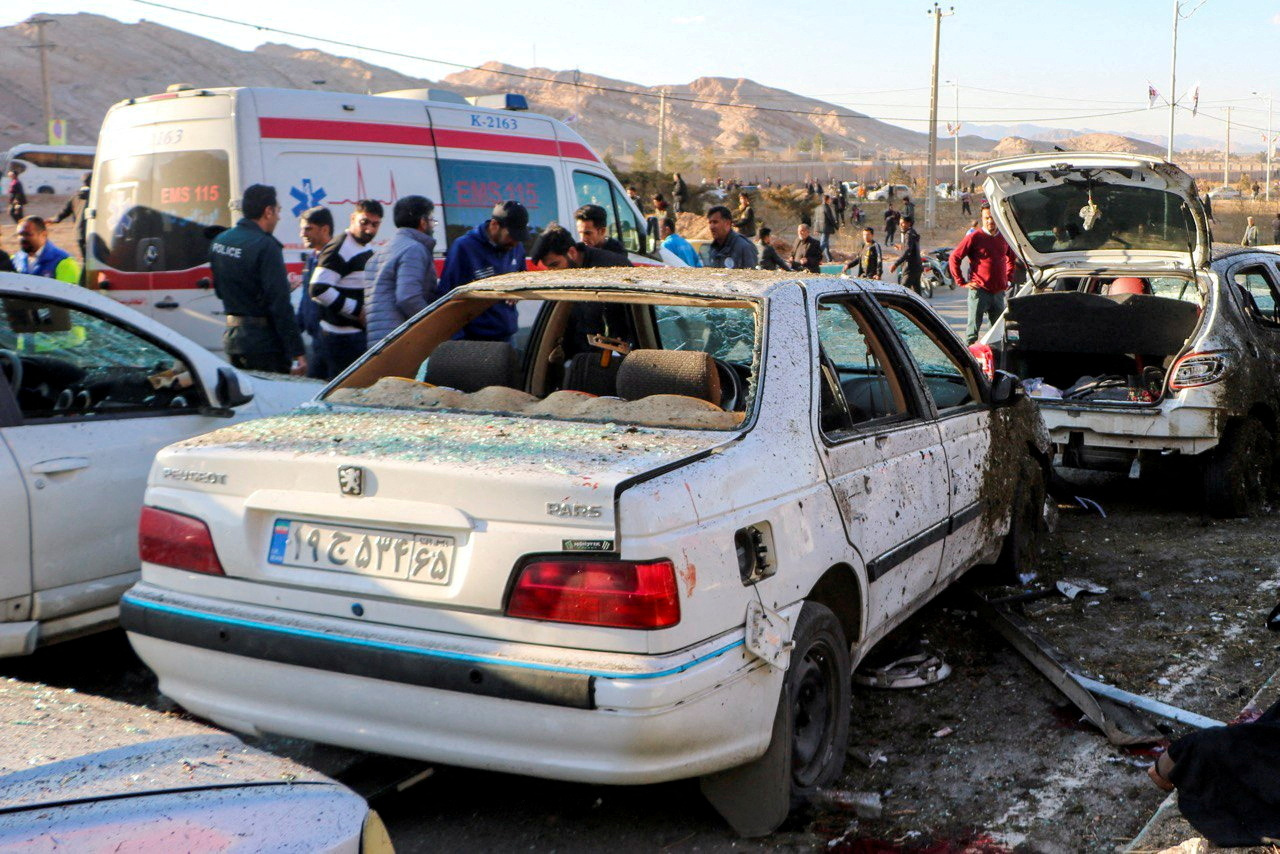 People gather at the scene of explosions during a ceremony held to mark the death of late Iranian...