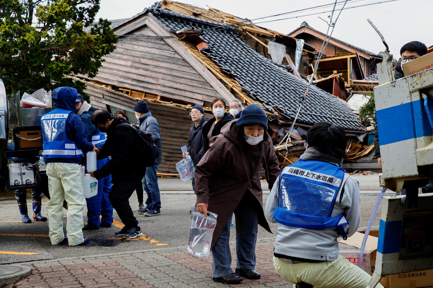 People line up to collect water, in the aftermath of the earthquake, in Wajima, Ishikawa...