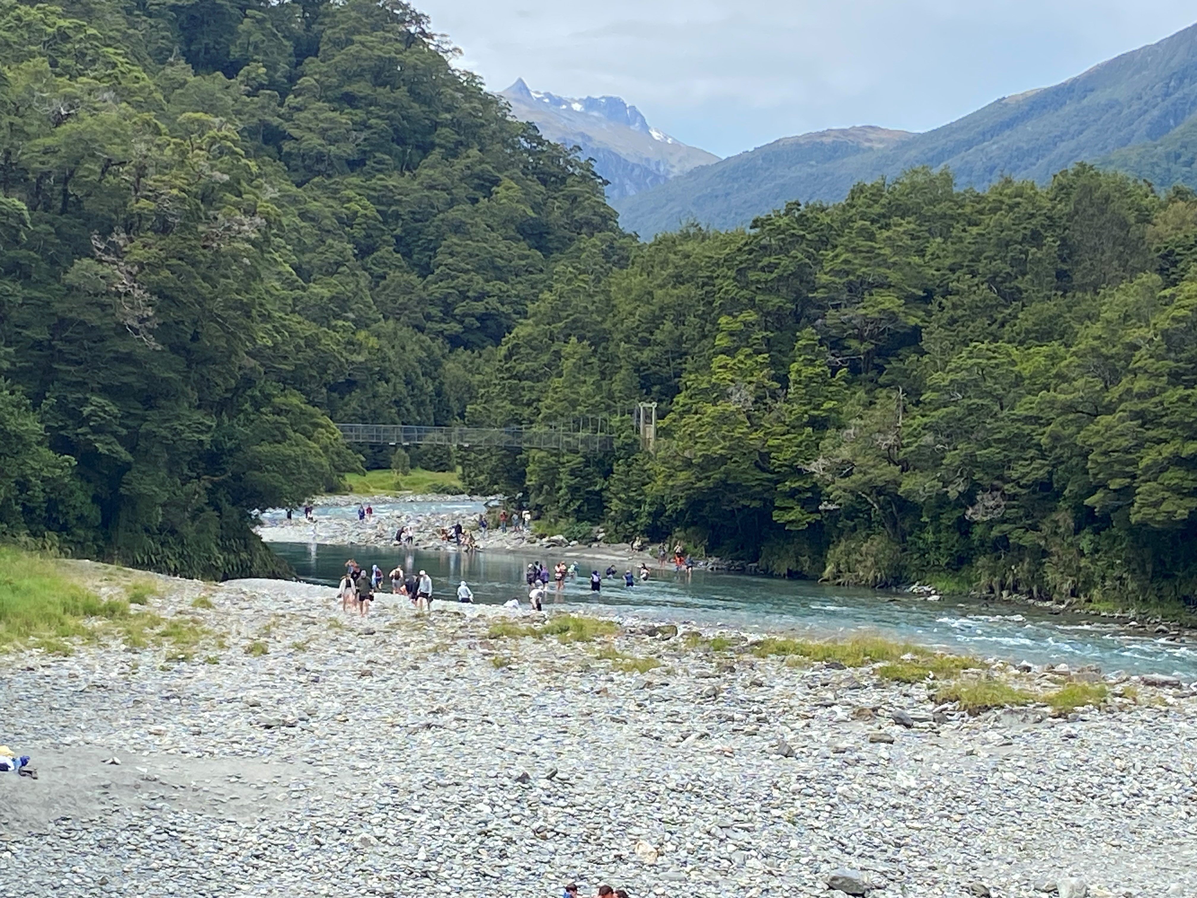 People cross the Makarora River to reach the Blue Pools.