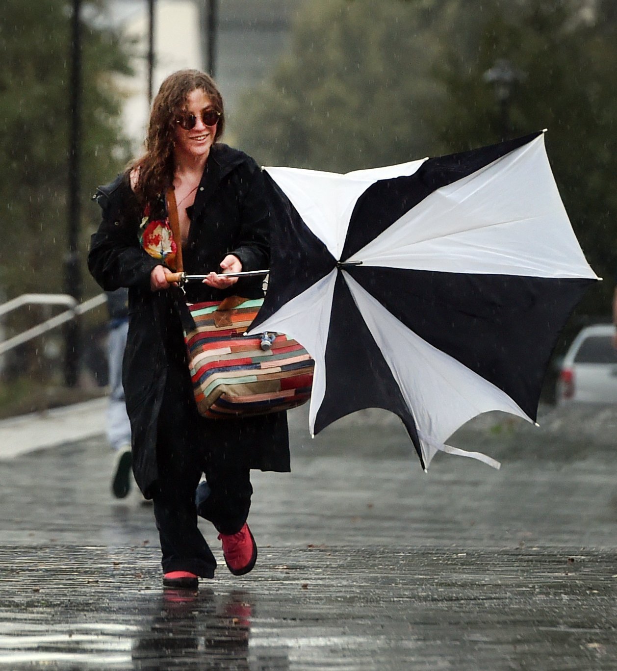 Student Sequoia Perkins, 20, walks with a broken umbrella, wild wind, low light and heavy rain,...