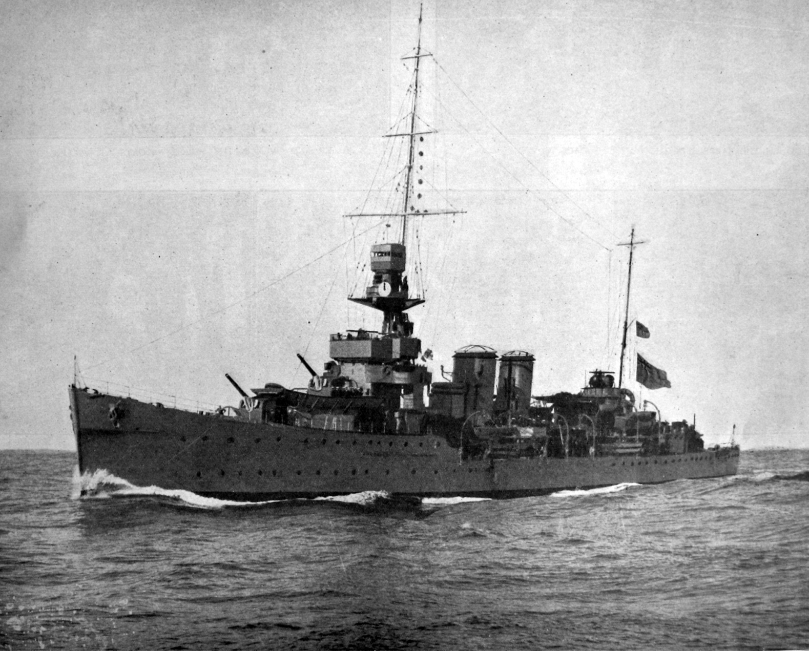 British light cruiser HMS Dunedin, pictured in fighting trim with all guns trained and cruising...