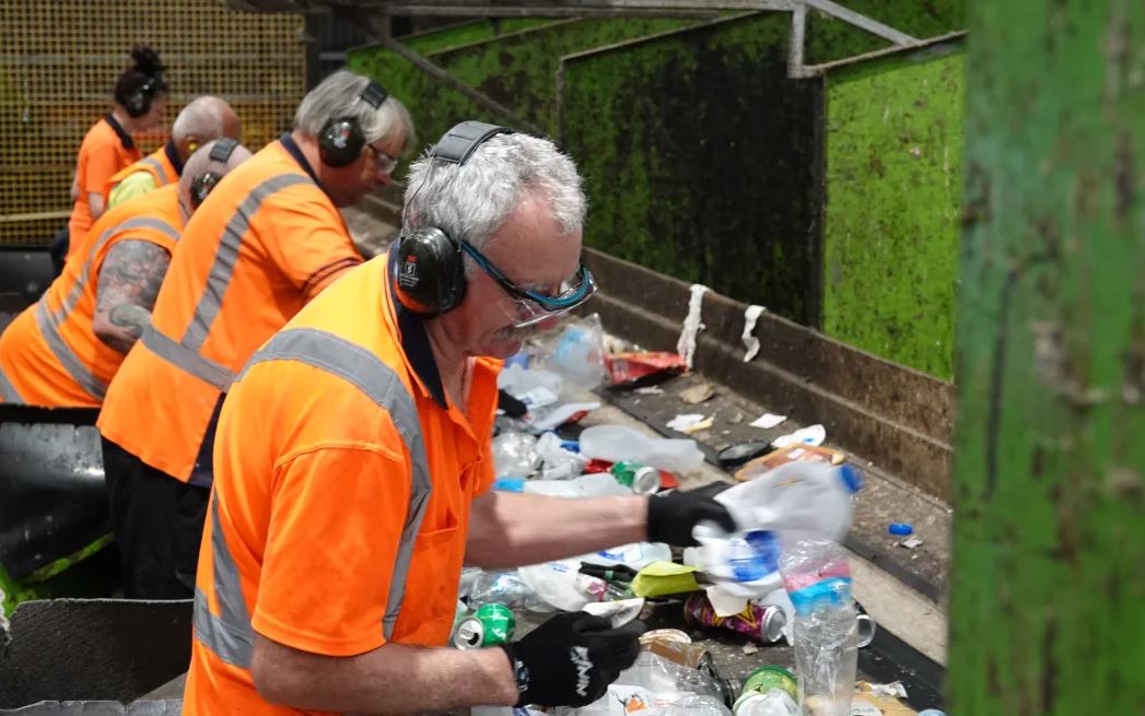 Workers manually separate the recycled items coming in on a conveyer belt. Photos: RNZ/Jimmy...