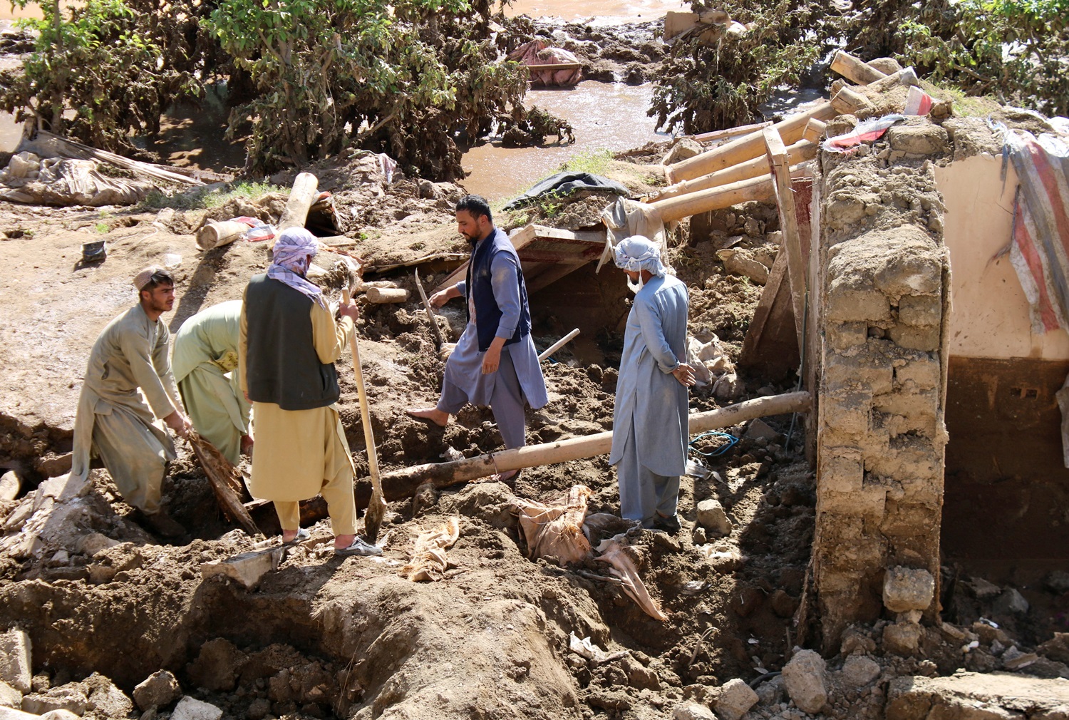 People remove debris from a flood-damaged house in Ghor Province, Afghanistan. Photo: Reuters