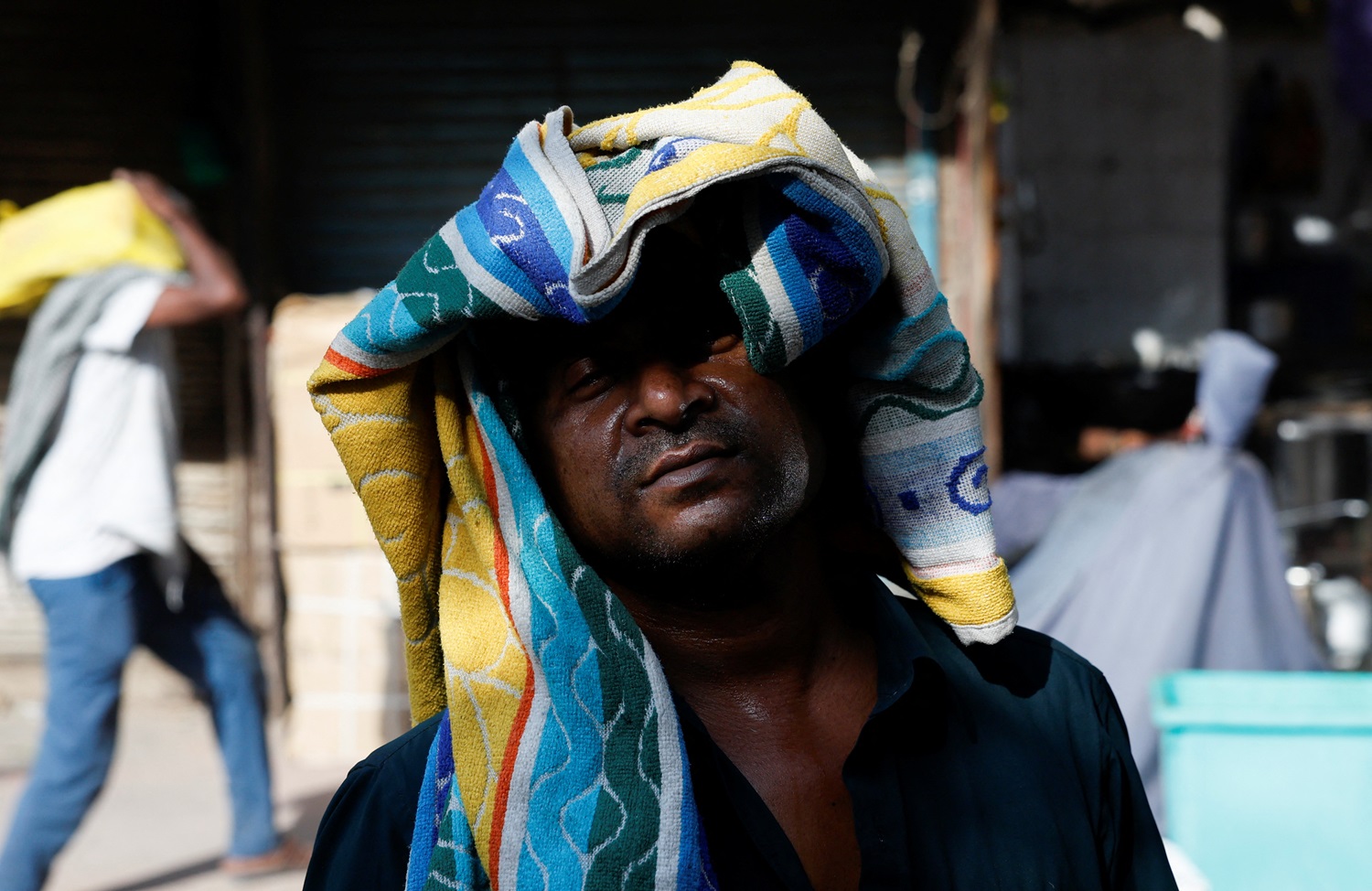 A man uses a towel to protect his head from the heat on a hot summer day in New Delhi on Tuesday....